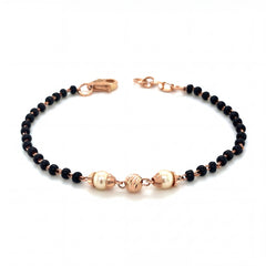 Elegant 18KT rose gold bracelet featuring black beads with pearl accents and textured gold centerpiece on a white background.