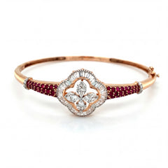 Elegant 18KT rose gold bangle featuring ruby-studded sides with a floral diamond centerpiece on a white background.