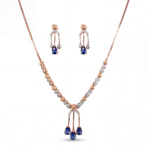 Beautiful 18KT rose gold necklace set showcasing sparkling diamond accents with blue teardrop gemstone pendant and matching dangling earrings on a white background.