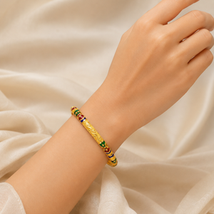 Elegant 18K yellow gold heritage bangle featuring intricate floral engraving, vibrant green, blue, and maroon Meenakari enamel detailing, and a timeless handcrafted traditional design. Luxury gold bracelet by Pachchigar Jewellers.