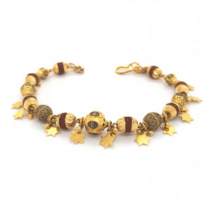Stylish 22KT yellow gold bracelet featuring textured designer beads, decorative accents, and dangling star charms on a white background.