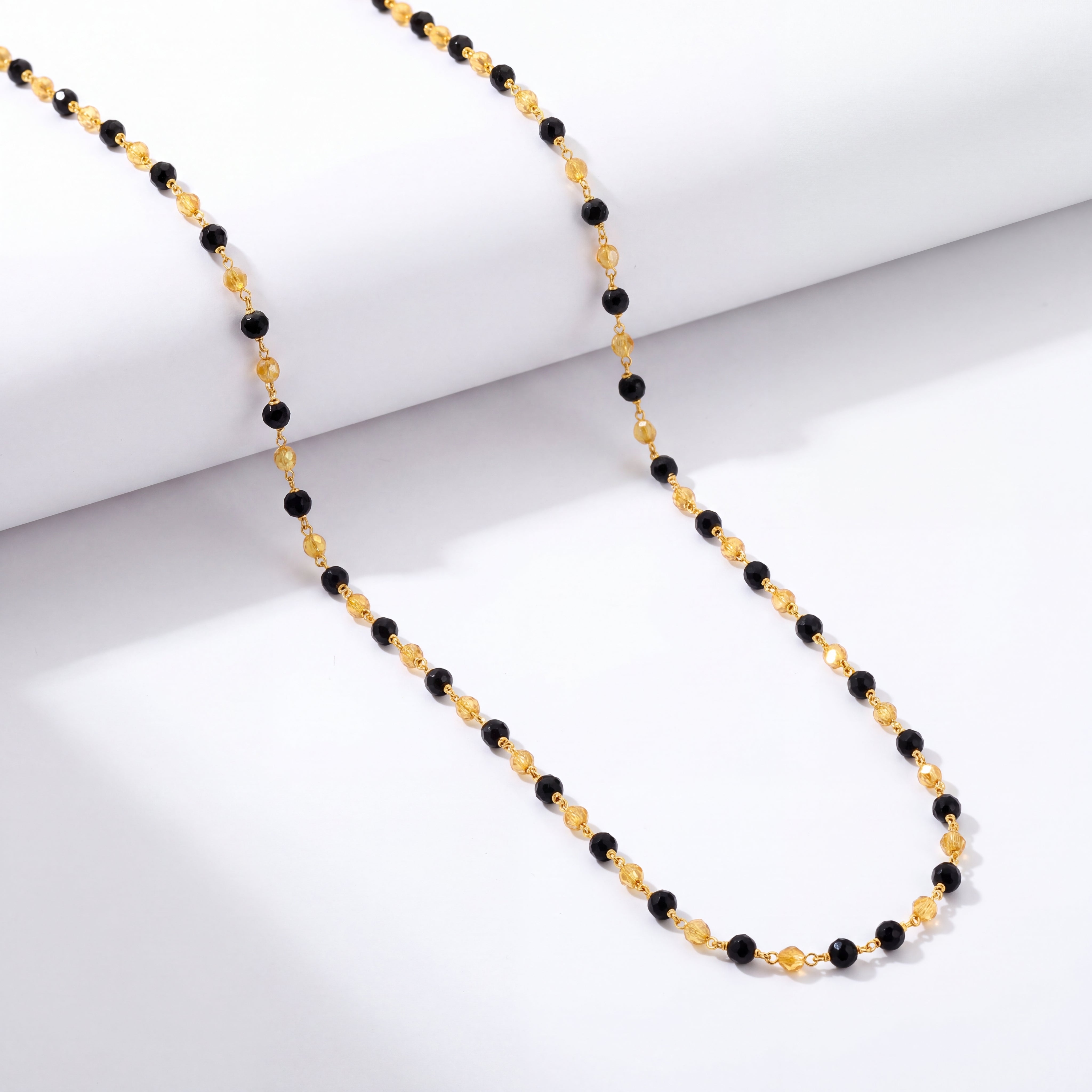 Elegant gold chain featuring evenly spaced black beads connected by delicate gold links, creating a simple and refined design.