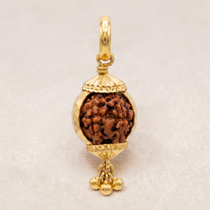 Yellow gold pendant featuring a spherical Rudraksha bead encased in a decorative gold frame with textured caps and small dangling gold beads, symbolizing spirituality and elegance.