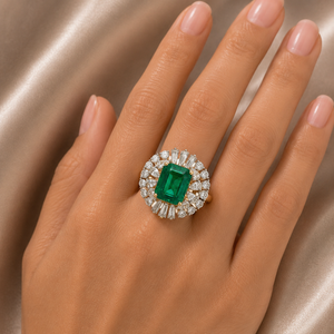 Exquisite gold ring featuring a vivid rectangular emerald-cut green gemstone surrounded by a halo of round and baguette diamonds, creating a luxurious statement design.