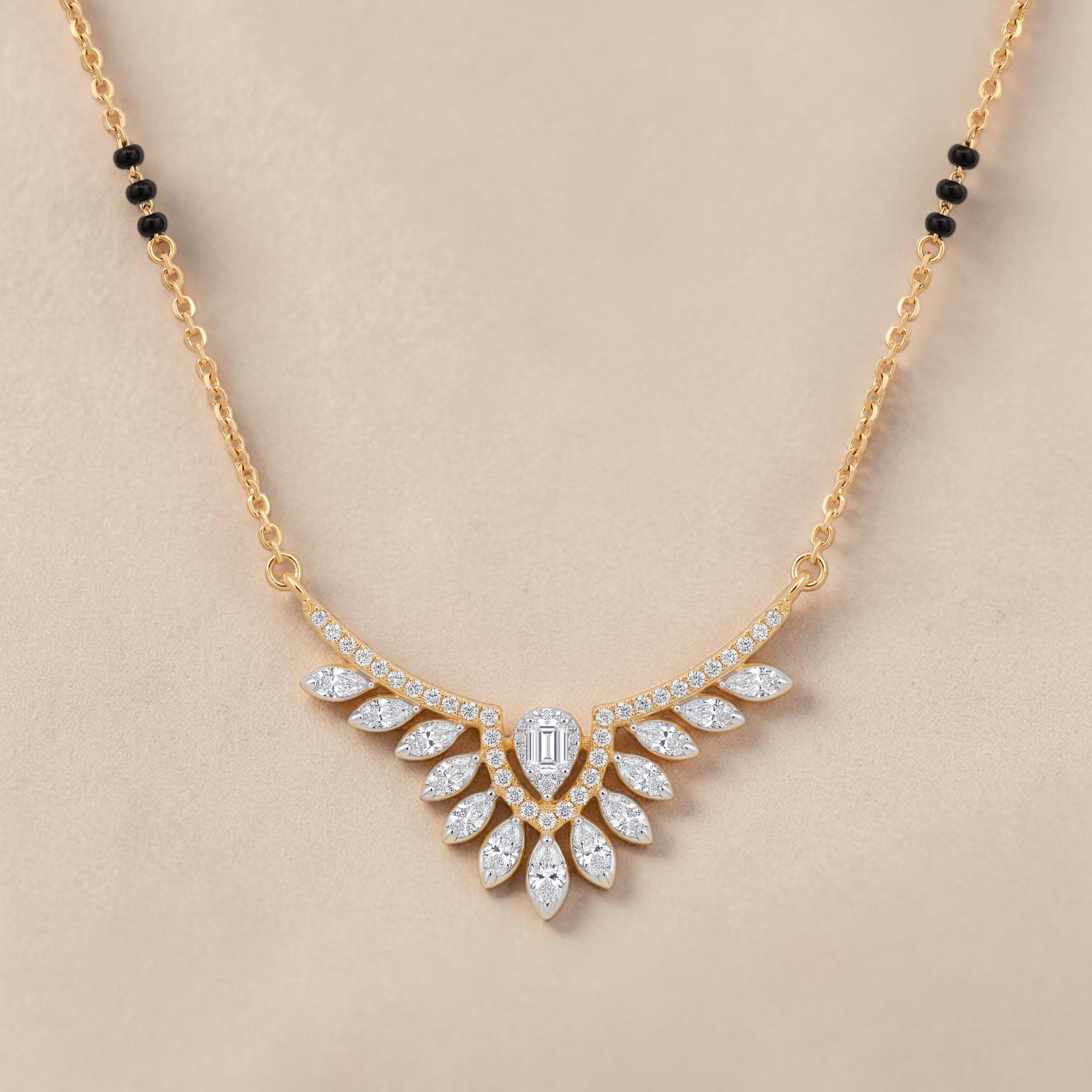 Elegant gold mangalsutra necklace featuring black beads and a dazzling diamond leaf wing pendant with a central emerald-cut diamond on a white background.