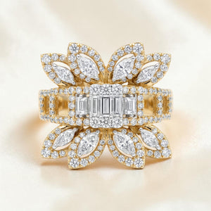 Yellow gold statement ring featuring a central baguette diamond cluster, surrounded by marquise-shaped diamond petals and pavé-set diamonds forming an elegant floral design with a wide diamond-studded band.