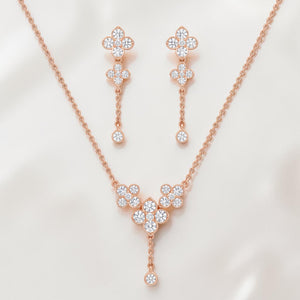 Elegant rose gold diamond jewelry set featuring a floral drop pendant necklace with matching dangling floral earrings on a white background.