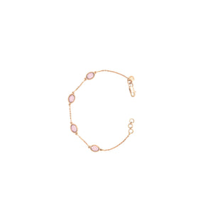 Elegant rose gold bracelet featuring oval pink gemstones spaced along a delicate chain with an adjustable clasp on a white background.