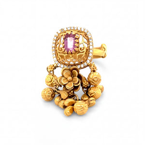 Traditional yellow gold ring featuring a pink gemstone centerpiece with diamond accents, intricate filigree detailing, and floral ghungroo danglers for a rich ethnic statement look.