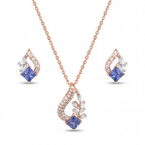 Elegant 18KT rose gold pendant set featuring blue princess-cut gemstone pendant with diamond accents and matching earrings on a white background.