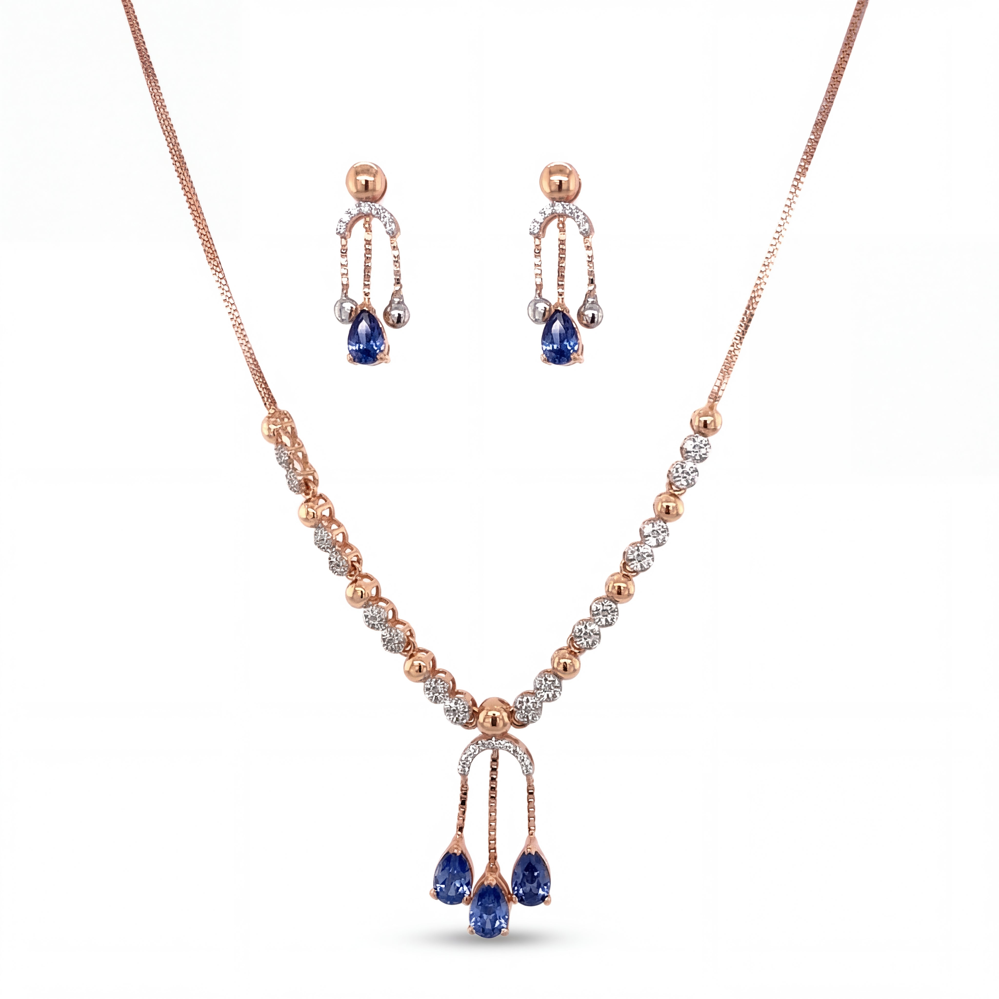 Beautiful 18KT rose gold necklace set showcasing sparkling diamond accents with blue teardrop gemstone pendant and matching dangling earrings on a white background.