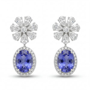 Elegant 18KT white gold drop earrings featuring oval blue tanzanite gemstones with diamond halo and floral diamond tops on a white background.