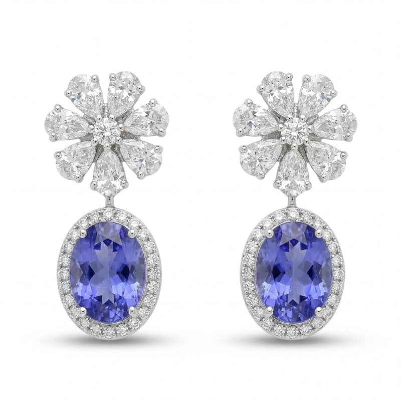 Elegant 18KT white gold drop earrings featuring oval blue tanzanite gemstones with diamond halo and floral diamond tops on a white background.