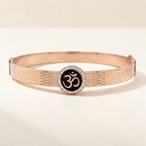 Elegant 18K rose gold designer kada featuring a textured finish, black enamel Om symbol, and a sparkling diamond halo. Spiritual luxury bracelet by Pachchigar Jewellers.