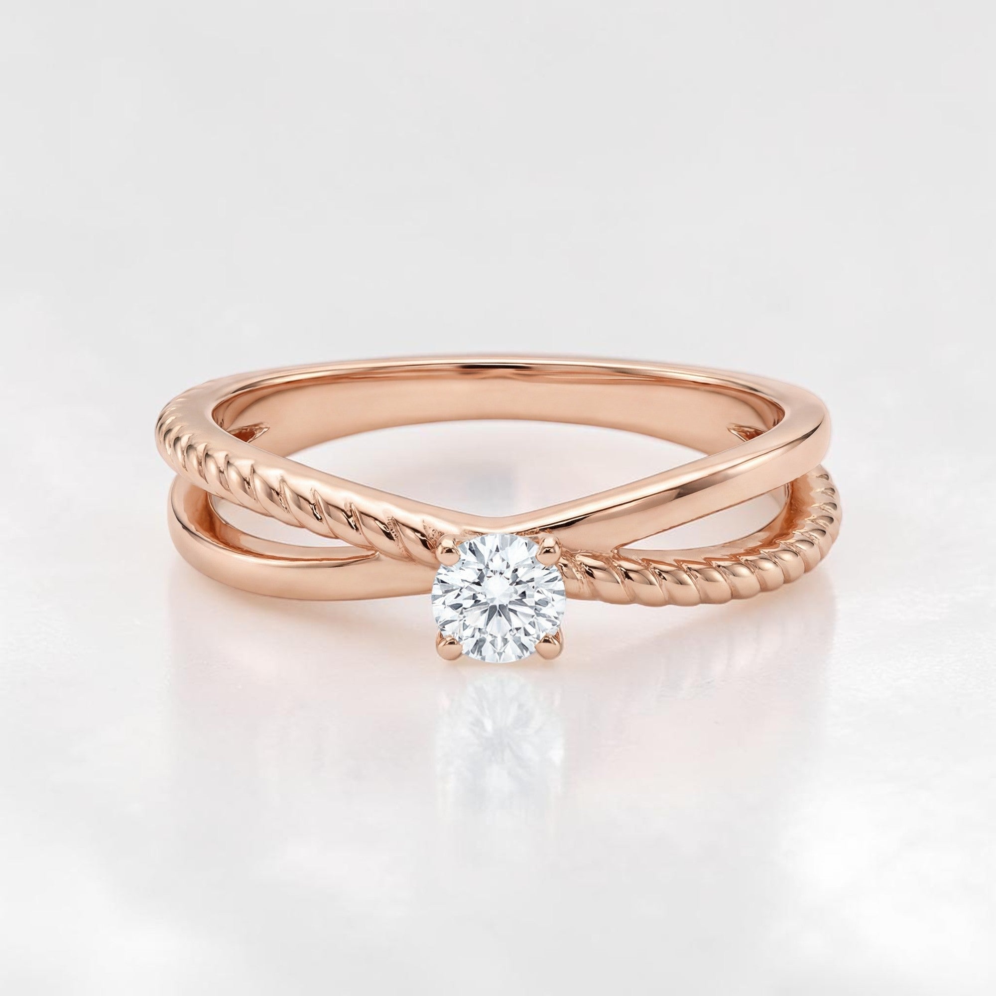 Elegant 18K rose gold crossover ring featuring a round solitaire diamond with smooth and twisted band detailing in a modern minimalist design.