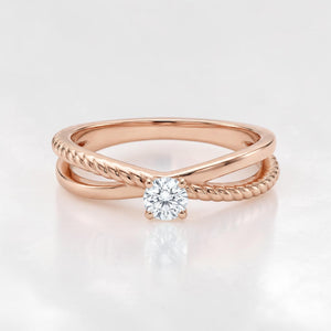 Elegant 18K rose gold crossover ring featuring a round solitaire diamond with smooth and twisted band detailing in a modern minimalist design.