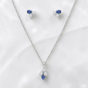 Luxurious 18K white gold sapphire diamond jewelry set featuring blue sapphire drop pendant with sparkling diamond cluster and matching earrings by Pachchigar Jewellers Ashokbhai