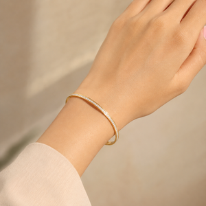 Elegant 18K yellow gold minimalist tennis bangle featuring a continuous row of brilliant round pavé-set diamonds, a sleek polished profile, and a timeless contemporary design. Luxury diamond bracelet by Pachchigar Jewellers.