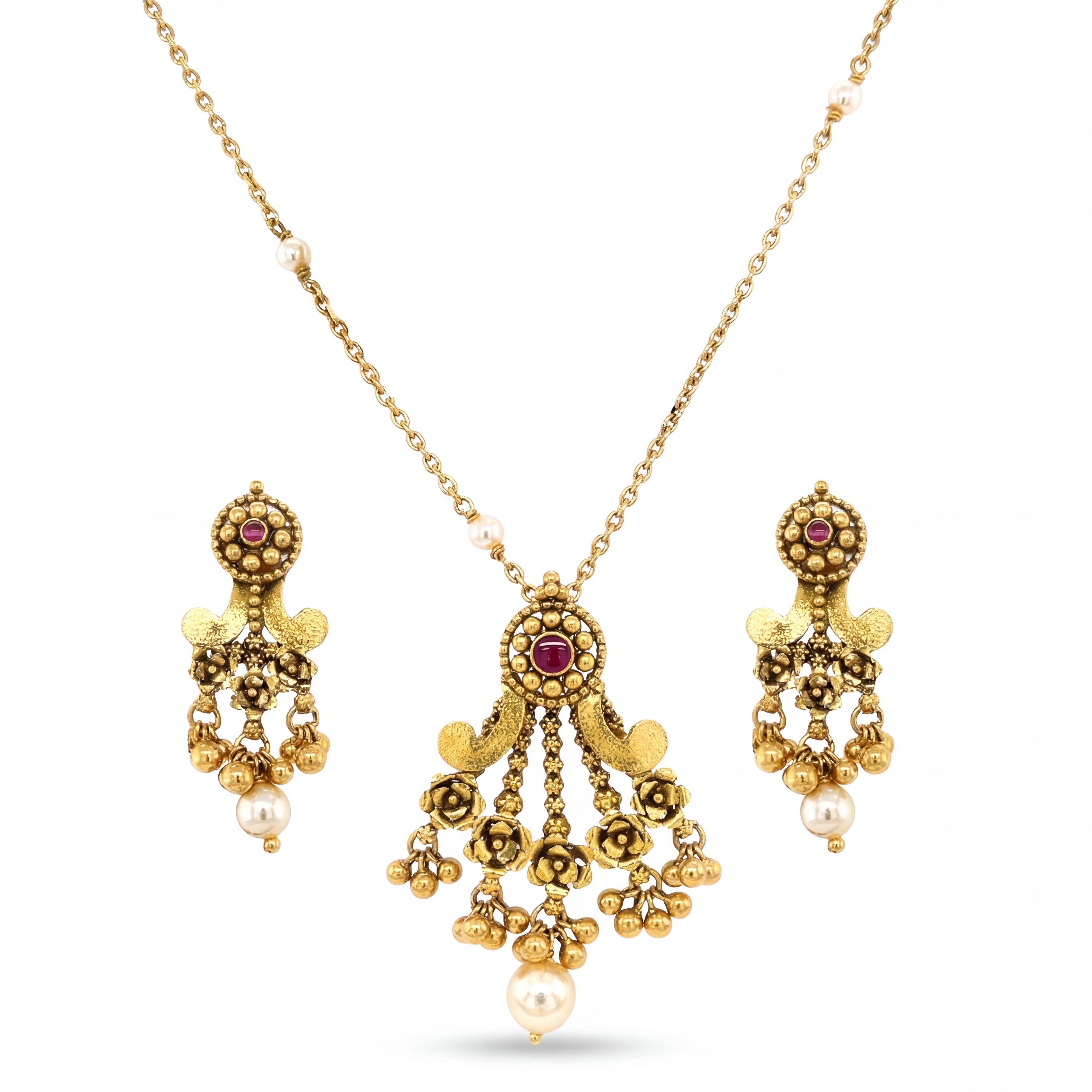 Graceful 22KT yellow gold pendant set featuring antique-style pendant with ruby accents, floral detailing, pearl drops, and matching dangling earrings on a white background.