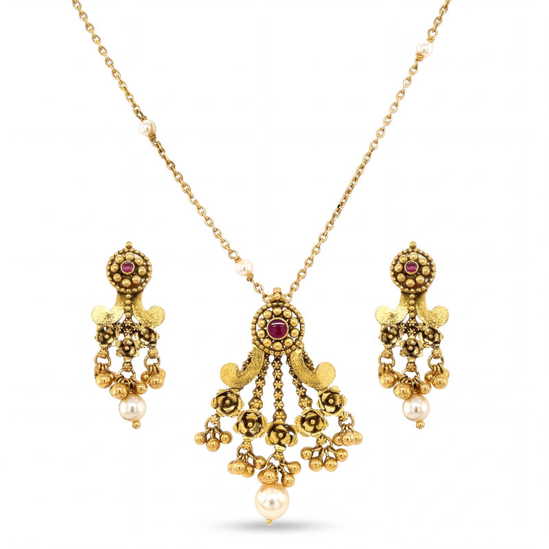 Graceful 22KT yellow gold pendant set featuring antique-style pendant with ruby accents, floral detailing, pearl drops, and matching dangling earrings on a white background.