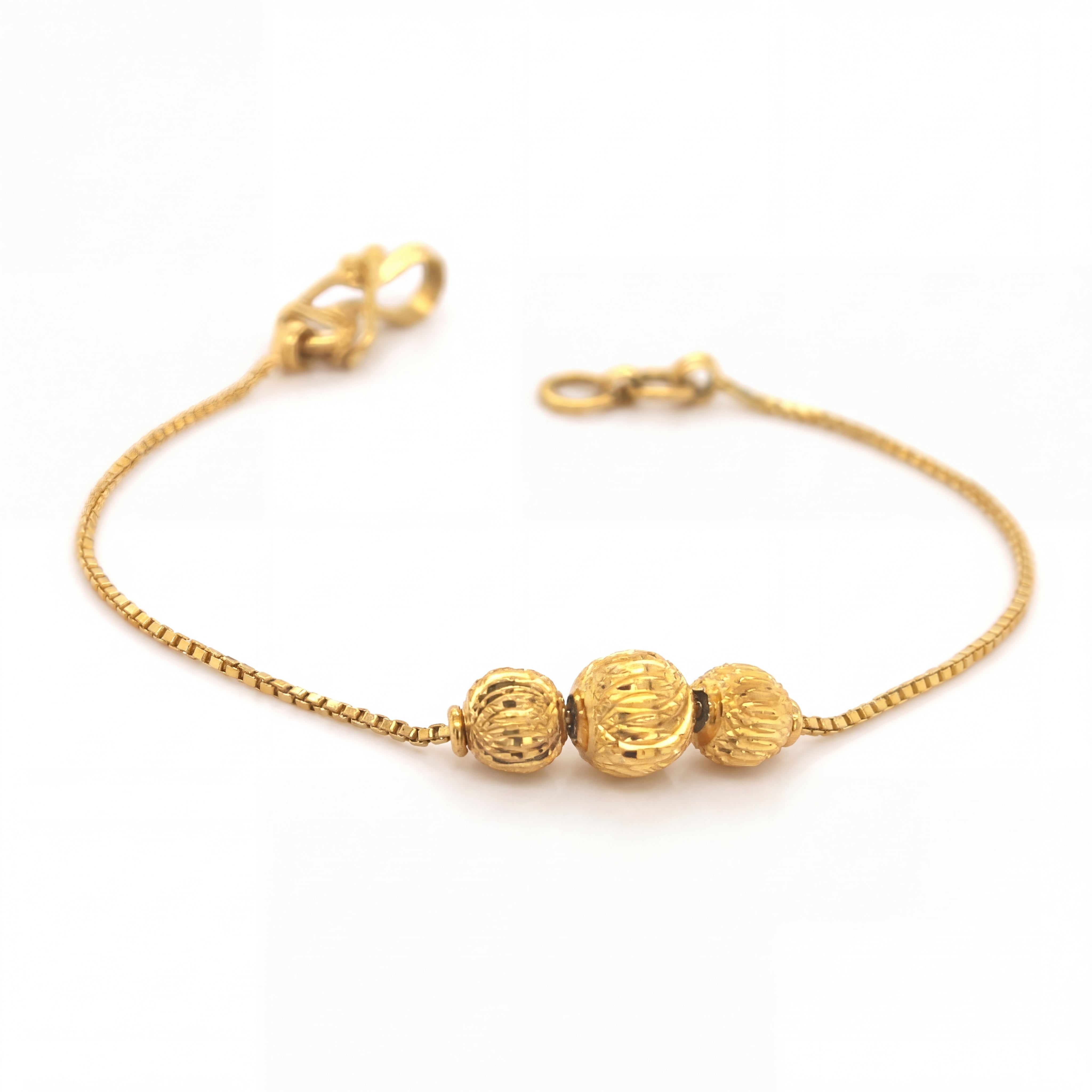 Elegant 22KT yellow gold bracelet featuring a delicate box chain with three textured gold bead accents on a white background.