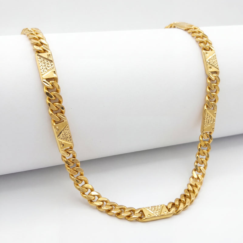 Bold 22K yellow gold Cuban link chain necklace featuring geometric textured designer plates and polished interlocking links displayed on a white cylindrical stand.