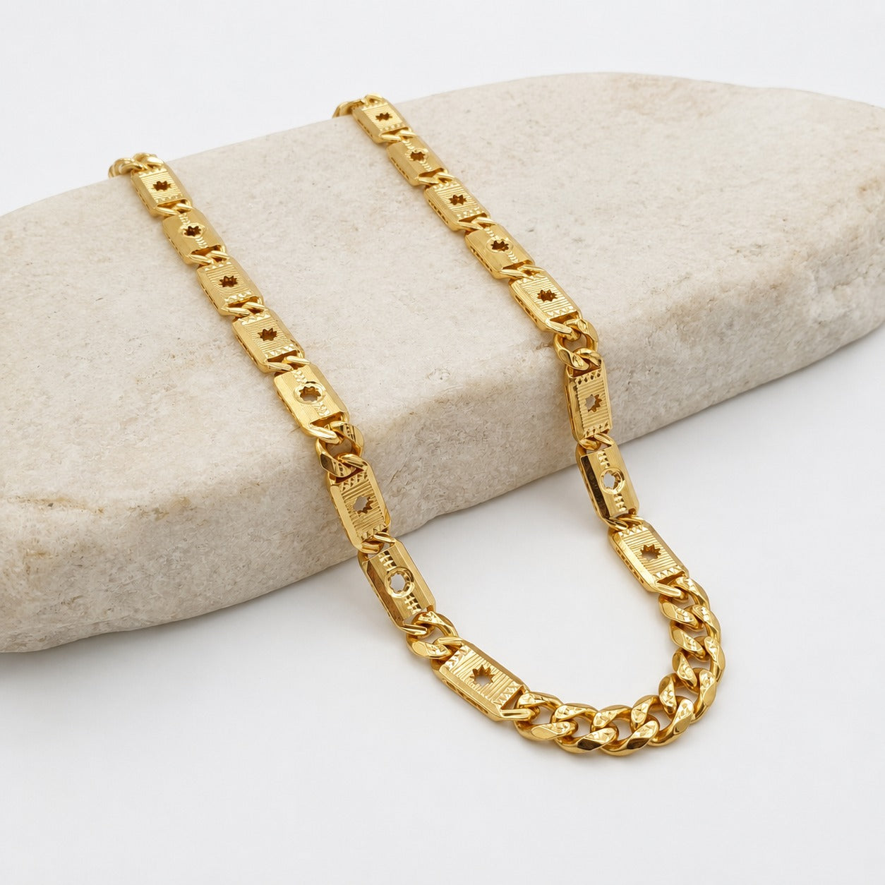 22K gold textured Cuban link chain featuring polished curb links, engraved rectangular accents with intricate detailing, and a secure clasp, designed for a bold and contemporary look.