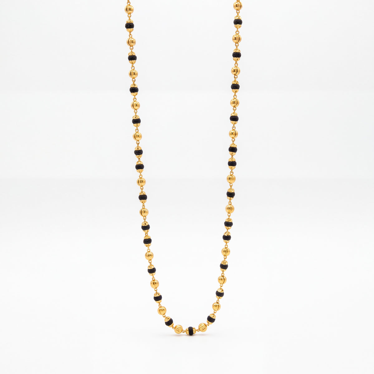 Elegant long gold necklace featuring alternating black beads and textured gold beads, connected with delicate gold links in a traditional design.