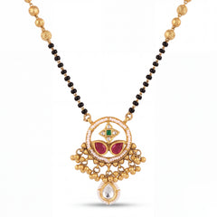 Traditional mangalsutra featuring black bead strands, handcrafted gold chain, designer pendant with ruby, emerald, pearl detailing, dangling gold charms, and festive ethnic styling for bridal and special occasions.
