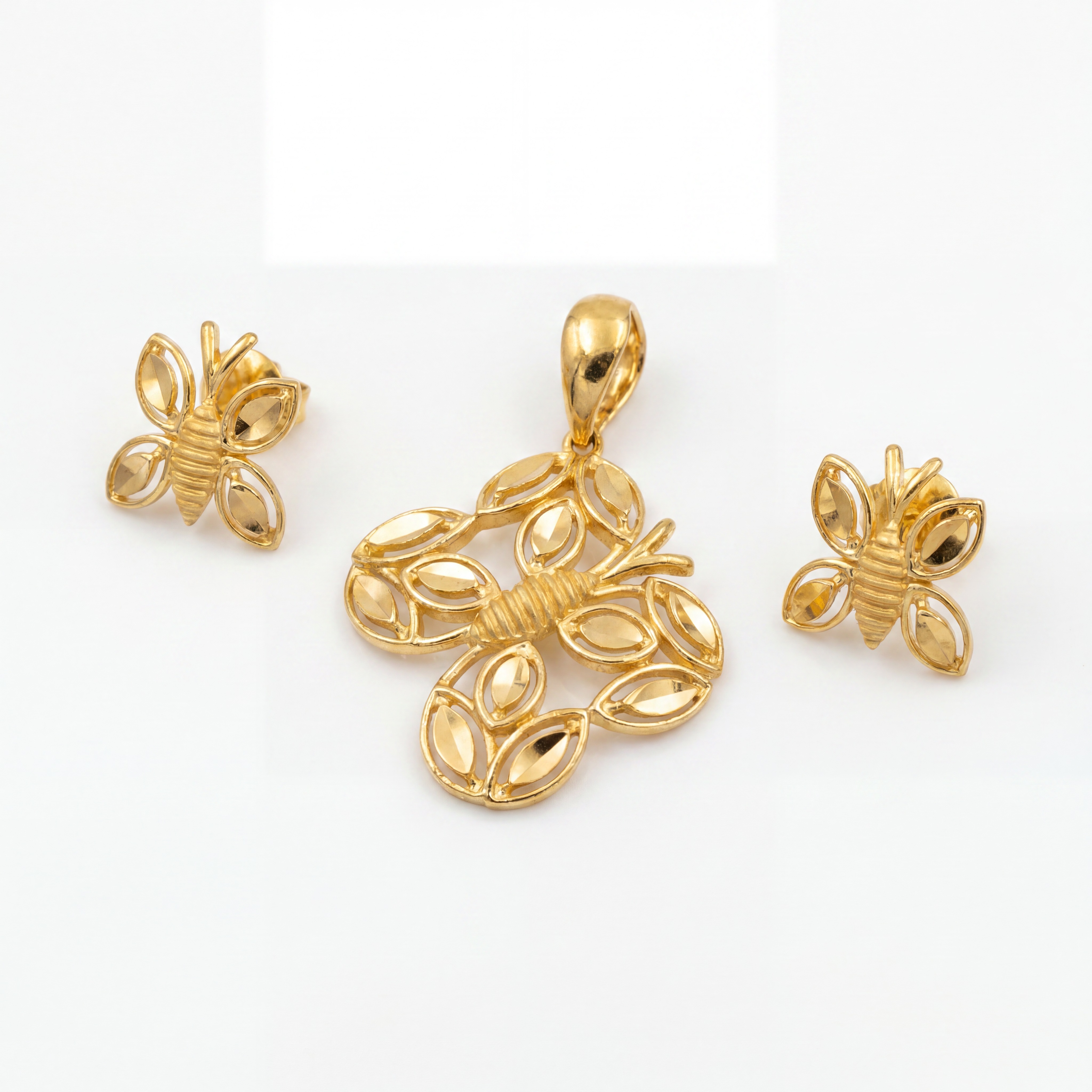 Elegant gold jewellery set featuring a bee-inspired pendant and matching earrings with intricate wing-shaped detailing, polished gold accents, and a graceful nature-inspired design.