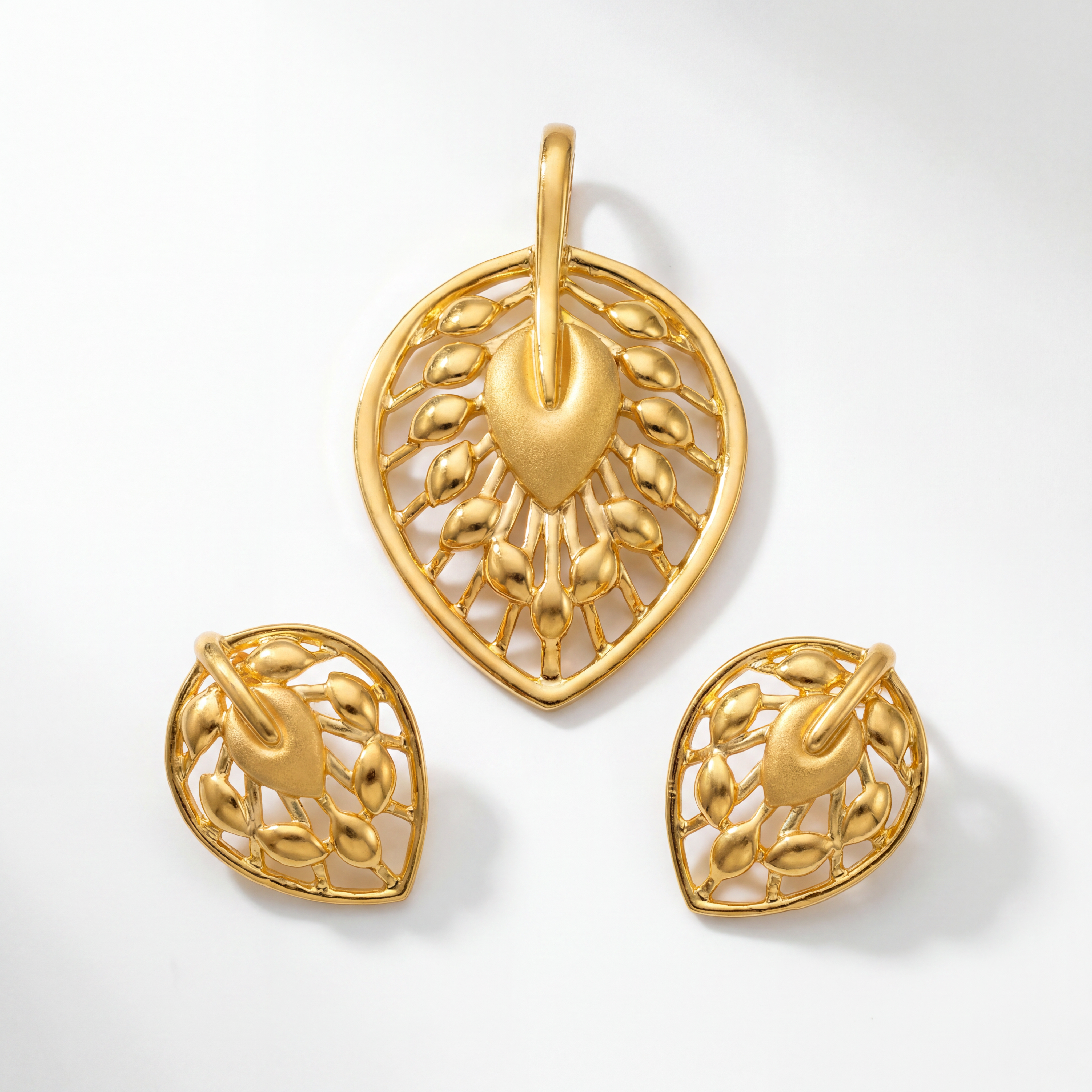 Elegant gold jewellery set featuring a heart-shaped pendant and matching earrings with intricate leaf-inspired openwork, a central heart motif, and polished gold detailing.