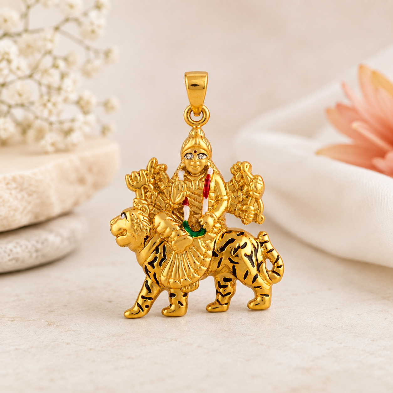 Intricately crafted gold pendant depicting Goddess Durga seated on a tiger, holding traditional weapons and featuring red and green gemstone accents.