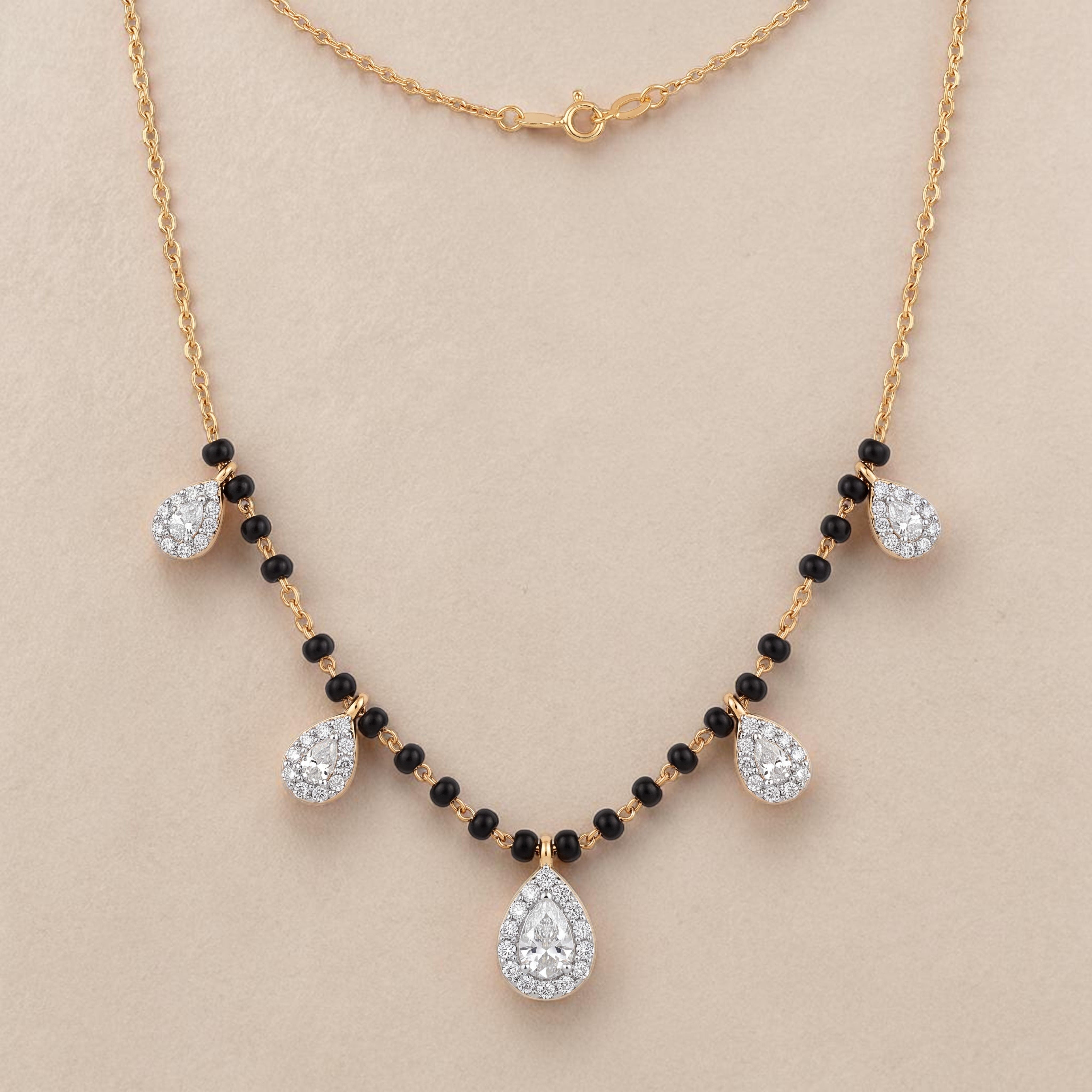 Elegant gold mangalsutra necklace featuring black beads and multiple sparkling teardrop-shaped diamond pendants on a white background.