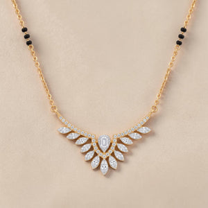 Elegant gold mangalsutra necklace featuring black beads and a dazzling diamond leaf wing pendant with a central emerald-cut diamond on a white background.