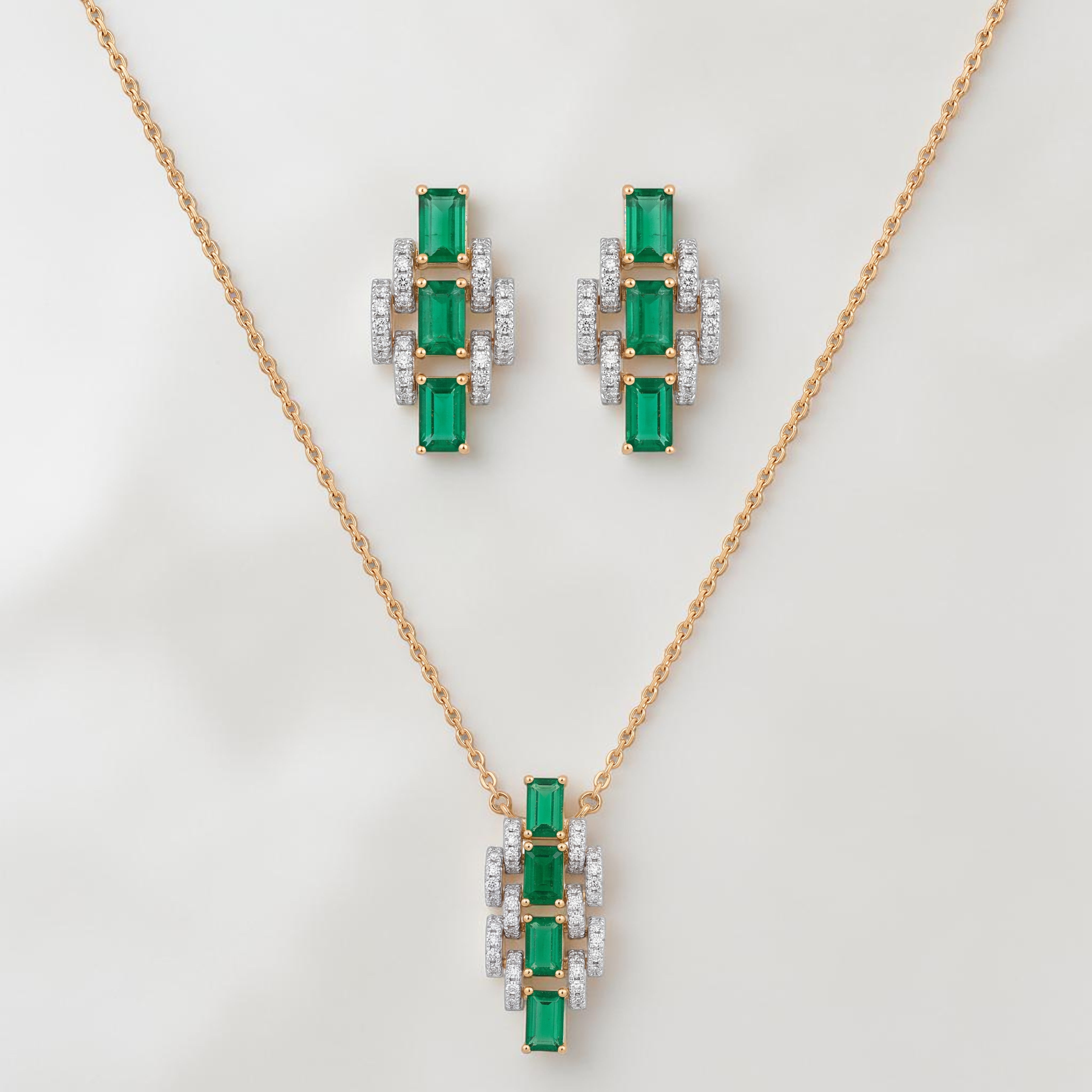 Elegant gold jewelry set featuring emerald-cut green gemstones with sparkling diamond accents in a pendant necklace and matching stud earrings on a white background.