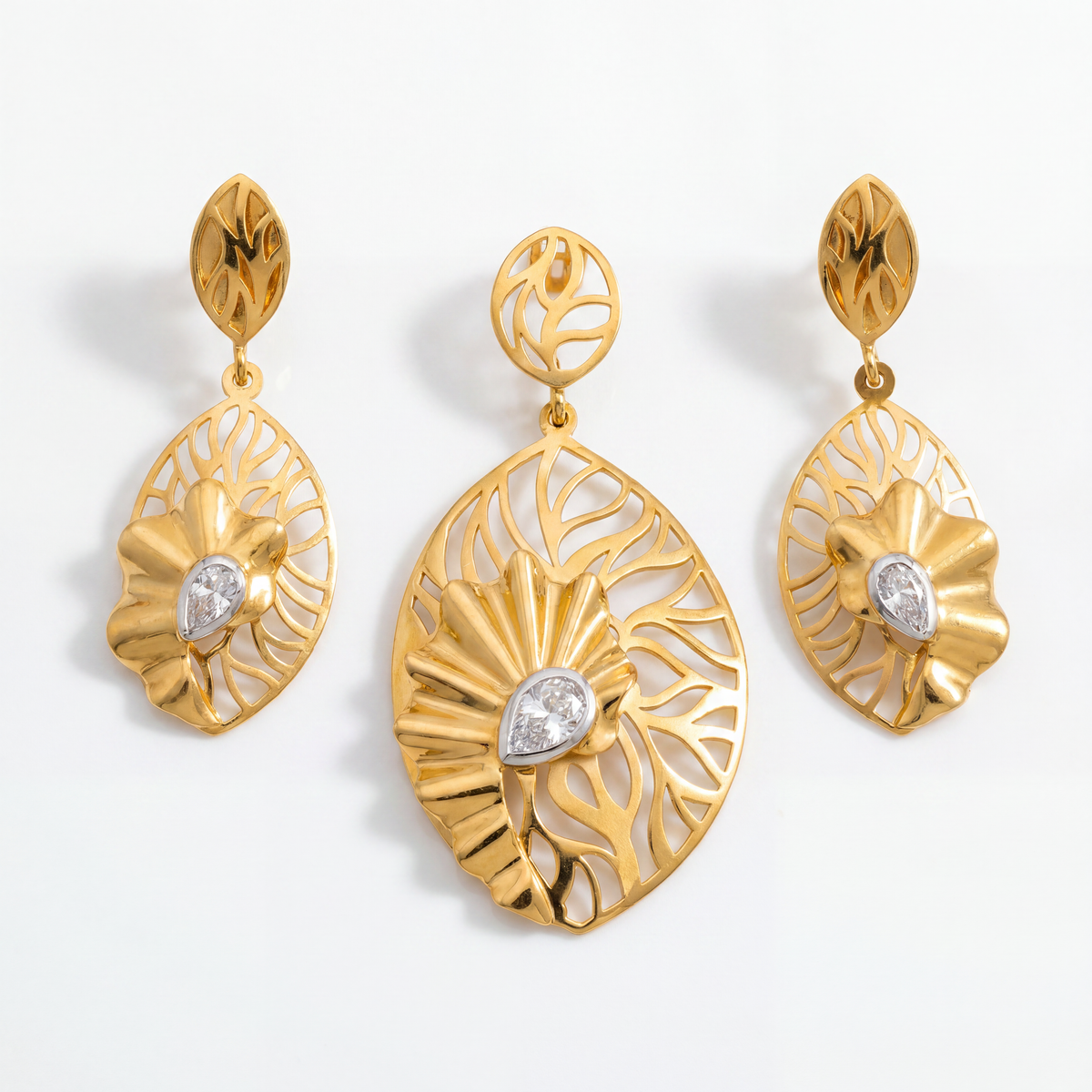 Elegant gold jewellery set featuring a leaf-inspired pendant and matching earrings with intricate openwork patterns, sculpted floral accents, and sparkling diamond details.