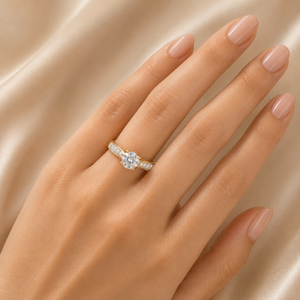 Elegant gold engagement ring featuring a round brilliant-cut center diamond with delicate pavé diamond accents along the curved band.