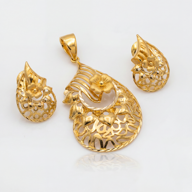 Elegant gold jewellery set featuring a floral filigree pendant and matching teardrop earrings with intricate openwork patterns, sculpted flowers, and polished gold detailing.