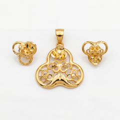 Intricately crafted gold jewellery set featuring a floral pendant and matching earrings with ornate openwork, curved motifs, and polished detailing.