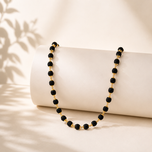 Elegant gold necklace featuring polished black textured beads connected by delicate gold links, creating a sleek and sophisticated long-chain jewellery design.
