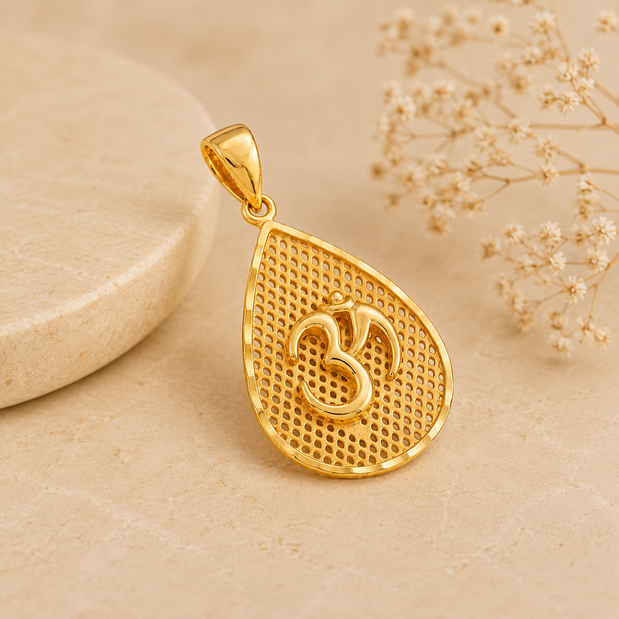 Elegant gold Om pendant featuring a raised Om symbol set against an intricate textured teardrop-shaped design with a polished gold finish.