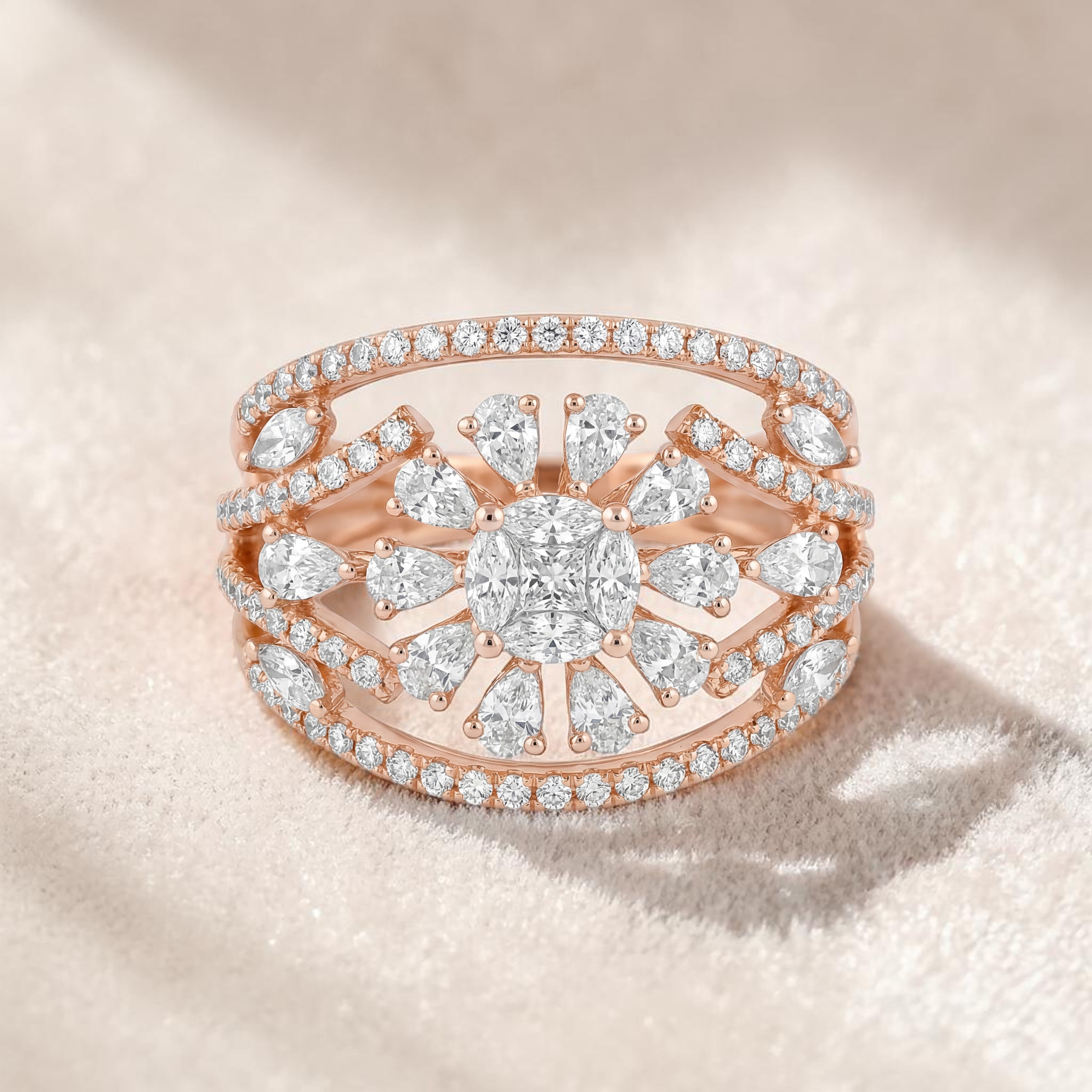 Rose gold wide ring featuring a central round diamond surrounded by pear-shaped diamonds in a sunburst pattern, with multiple pavé-set diamond bands creating an elegant layered design.
