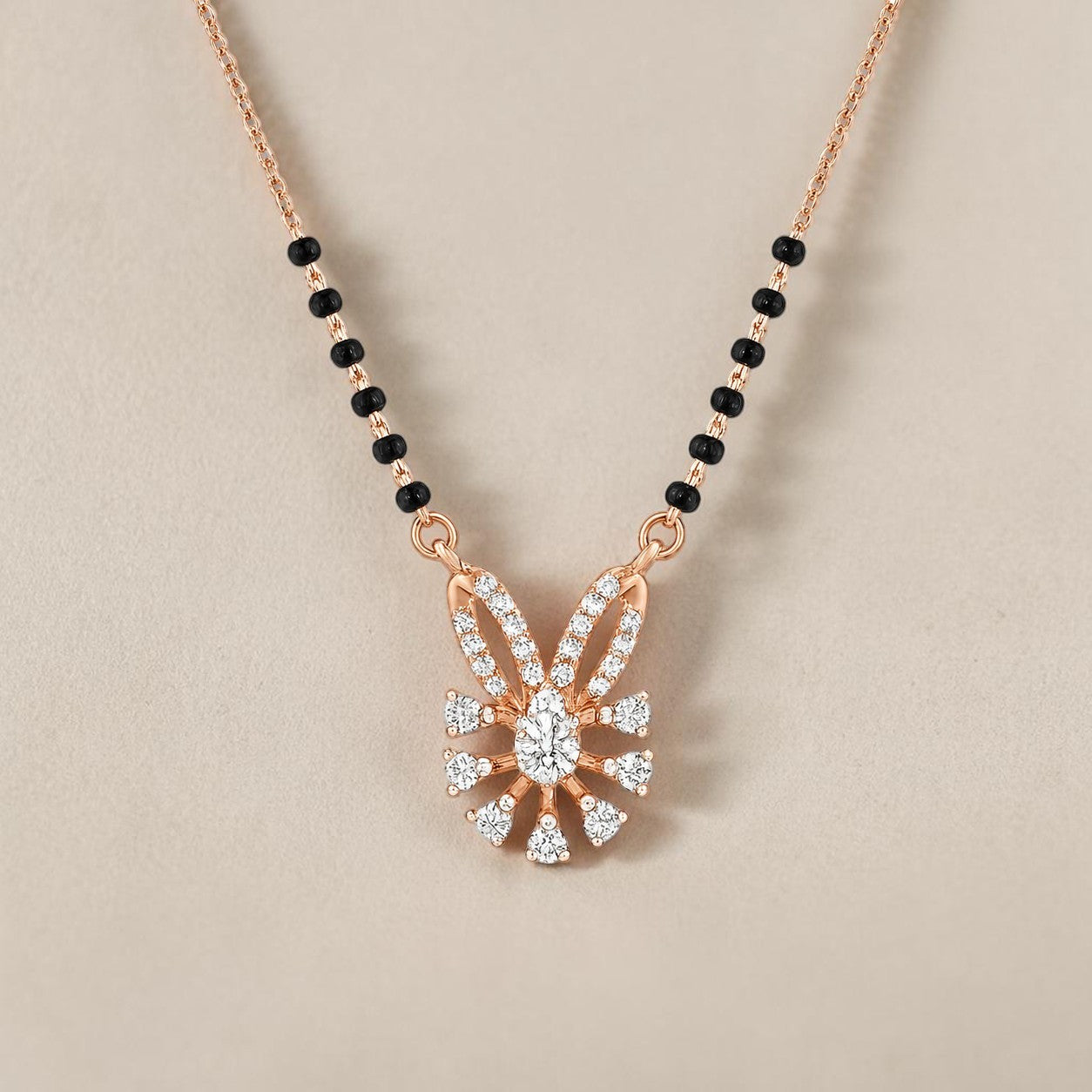 Elegant rose gold mangalsutra necklace featuring black beads and a sparkling floral-inspired diamond drop pendant with intricate detailing on a white background.