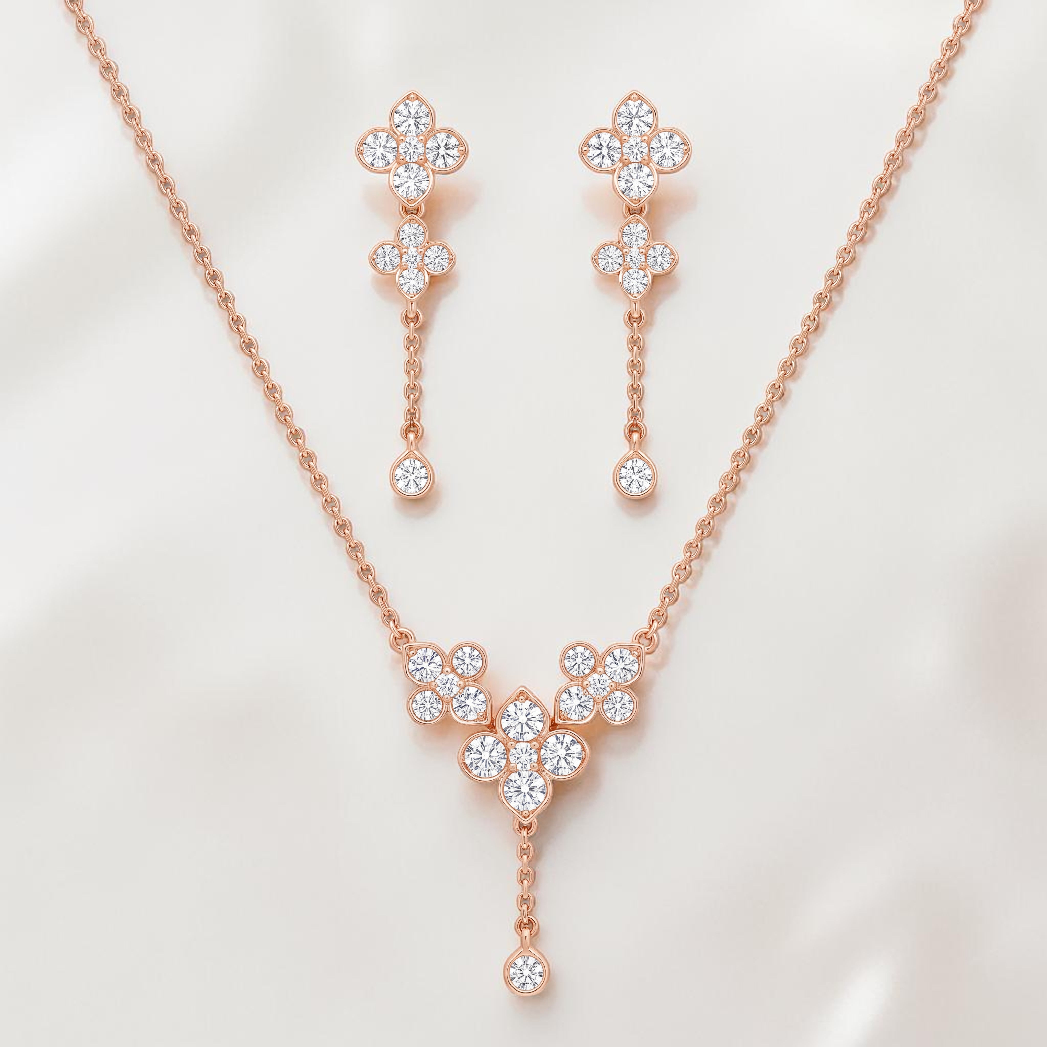 Elegant rose gold diamond jewelry set featuring a floral drop pendant necklace with matching dangling floral earrings on a white background.