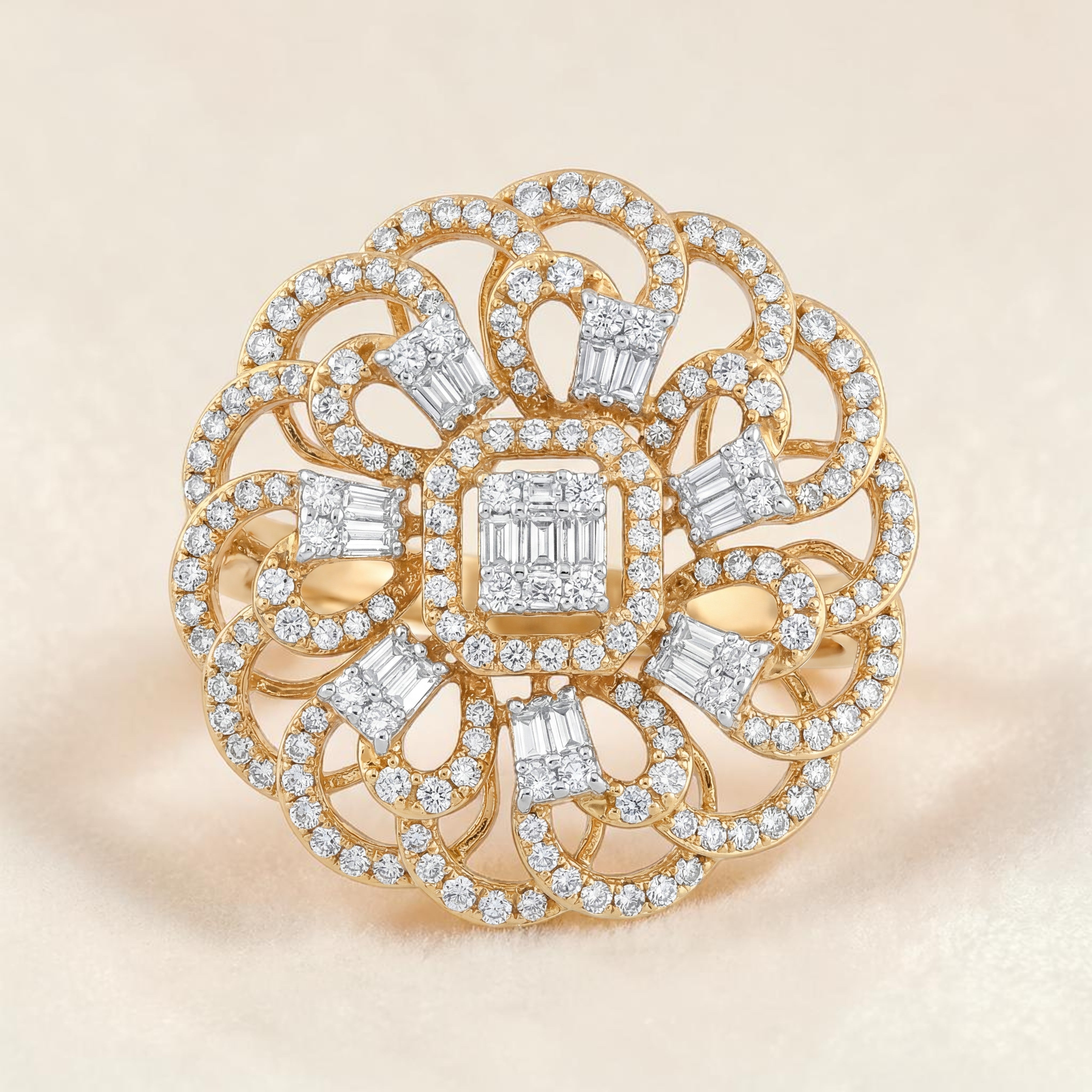 Elegant floral-inspired diamond ring featuring a square cluster center with baguette diamonds, surrounded by intricate looping patterns and round brilliant diamonds set in yellow gold.