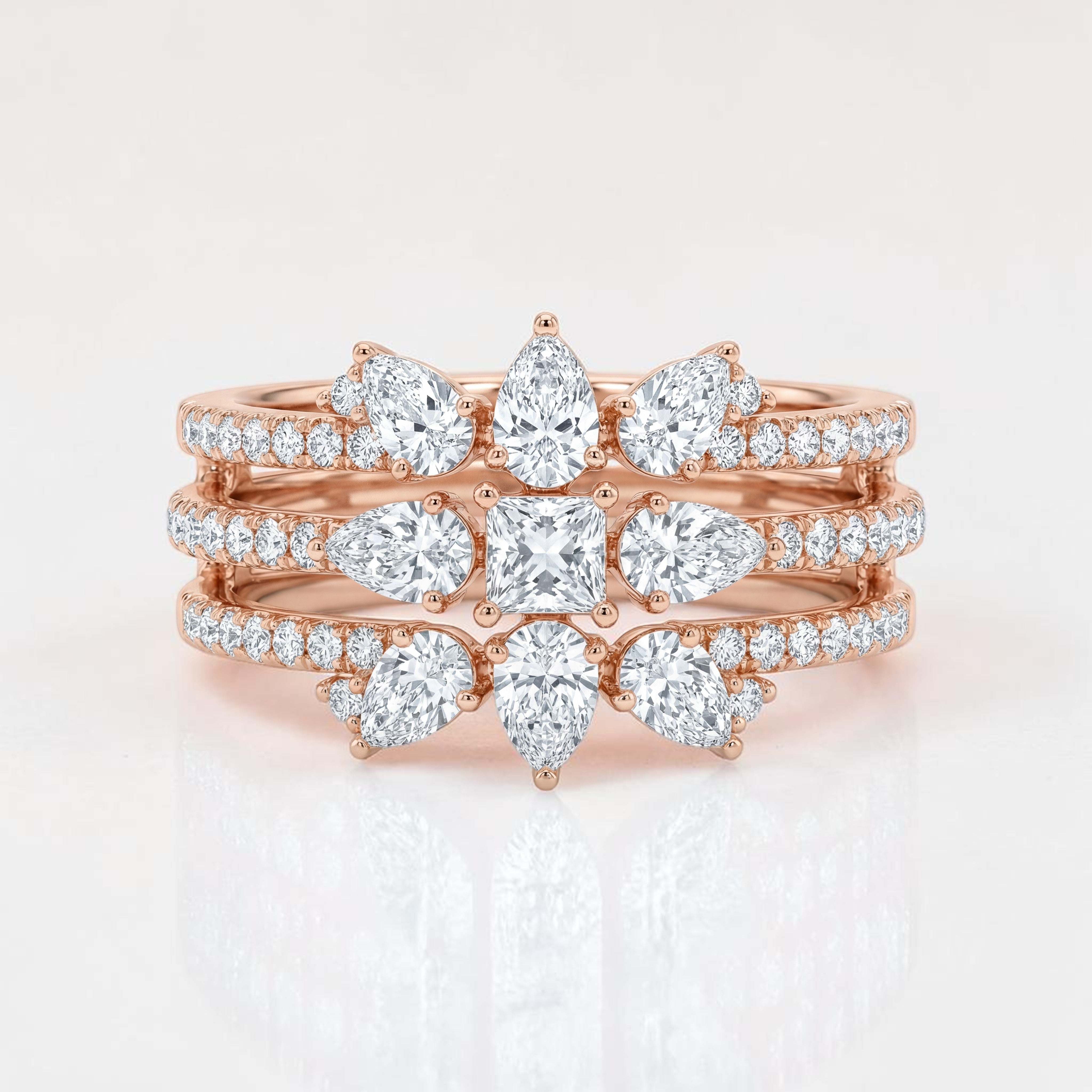 Rose gold multi-band ring featuring layered rows of pavé-set diamonds with pear-shaped and a central cushion-cut diamond arrangement, creating a crown-inspired, stacked statement design.