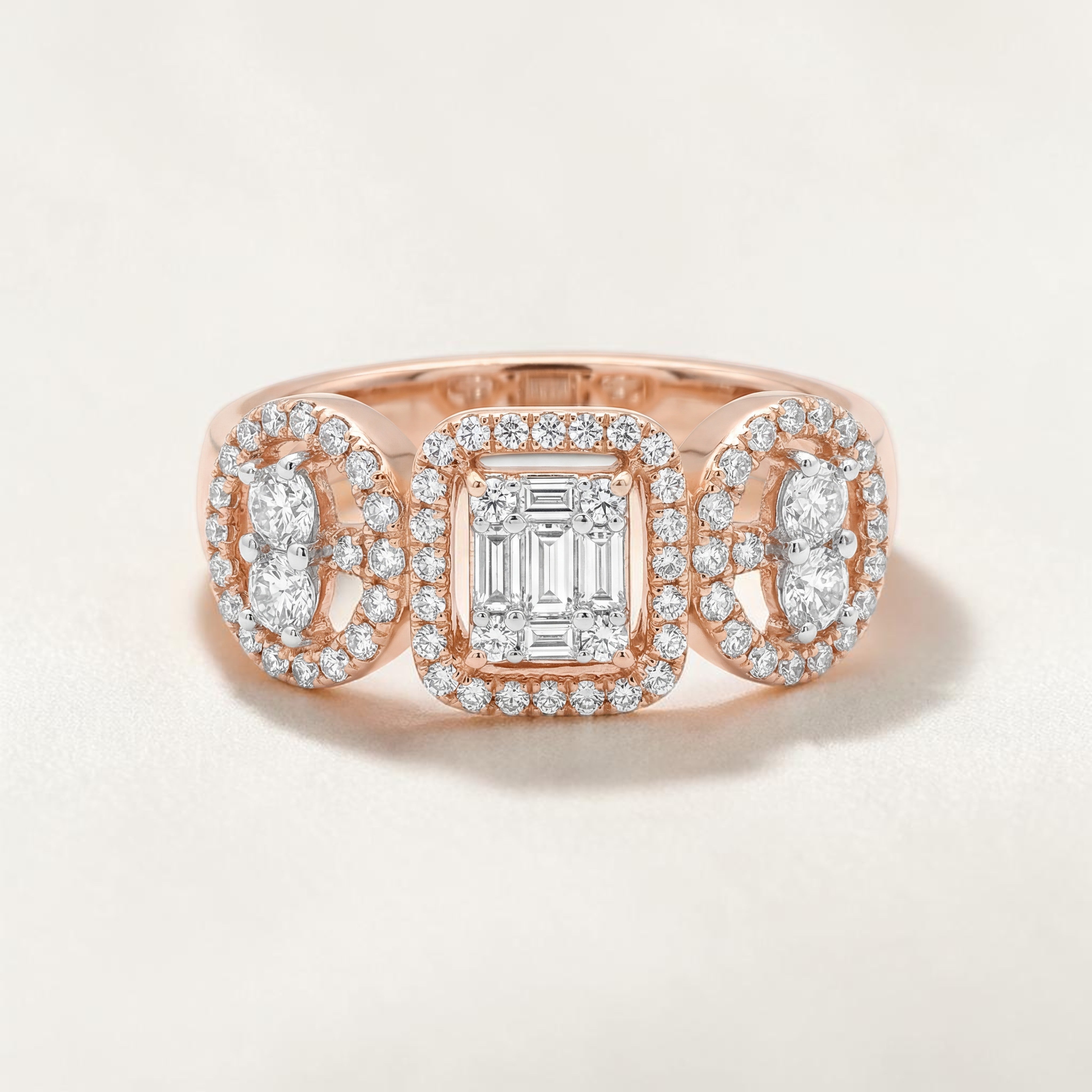 Rose gold ring featuring a central emerald-cut diamond framed by a halo, flanked by two oval diamond clusters with pavé halos, creating a balanced and elegant three-stone design.